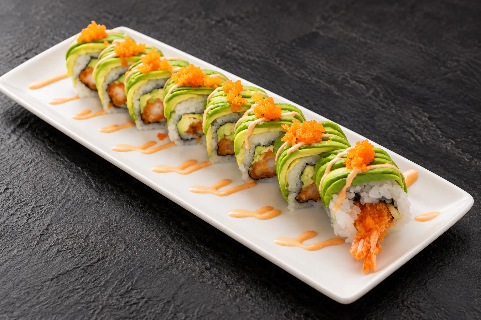 Avocado and tempura prawn roll on a white rectangular plate, dark slate background.