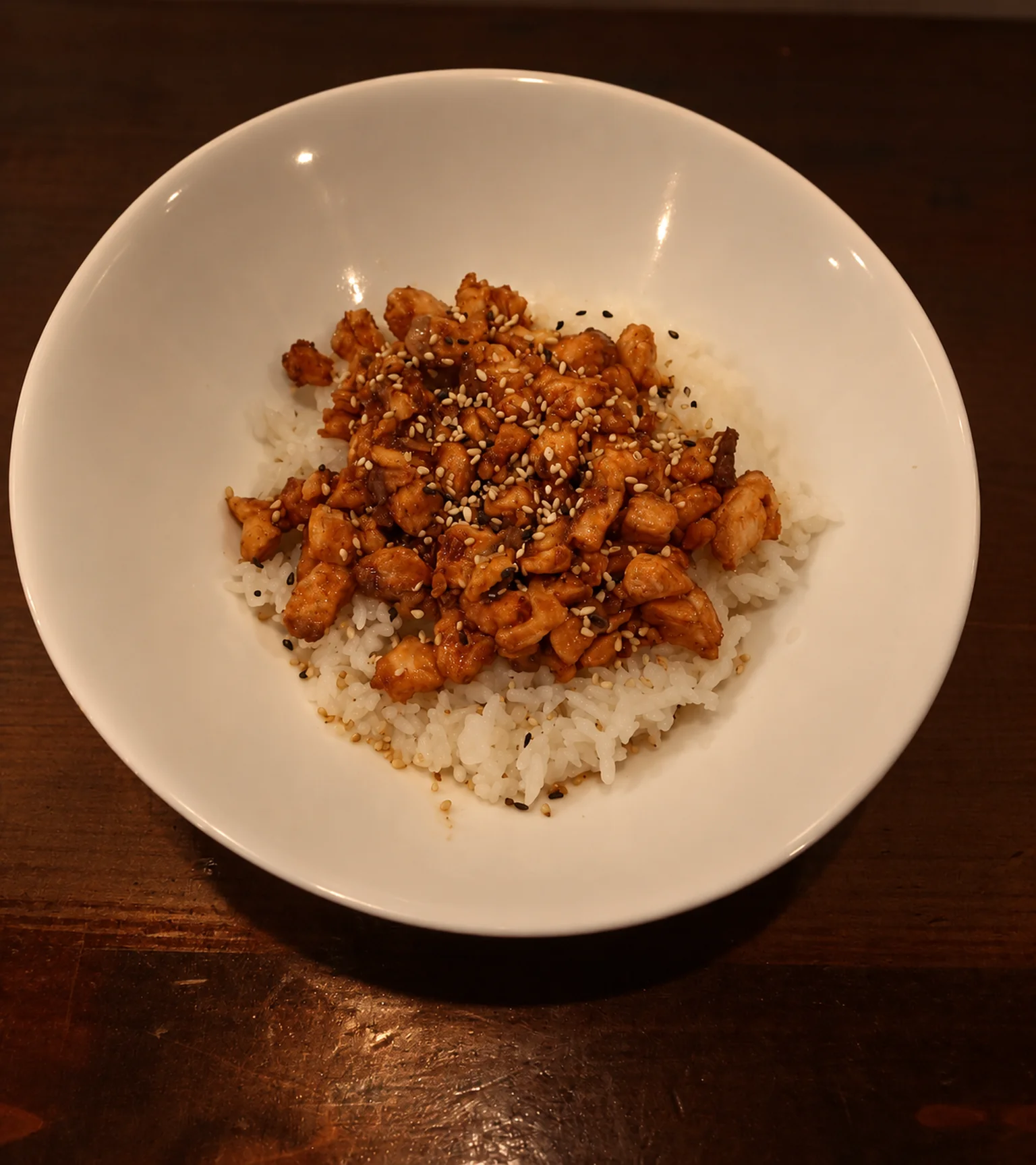 CH9: white bowl of topped rice on a dark wooden table, evening light.